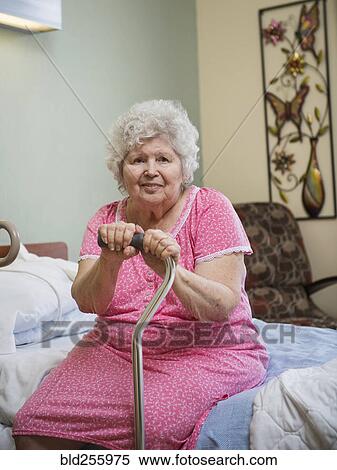 Smiling Caucasian woman sitting on bed leaning on cane View Large Photo Image Stock Photography - Smiling Caucasian woman sitting on bed leaning on cane. Fotosearch