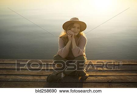 Smiling Caucasian woman sitting on dock of lake View Large Photo Image Stock Image - Smiling Caucasian woman sitting on dock of lake. Fotosearch