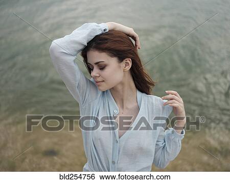 Stock Photograph - Smiling Caucasian woman standing near ocean. Fotosearch