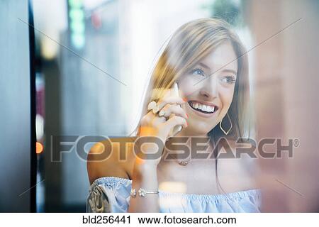 Stock Image - Smiling Caucasian woman talking on cell phone. Fotosearch
