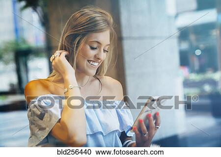 Stock Image - Smiling Caucasian woman texting on cell phone. Fotosearch