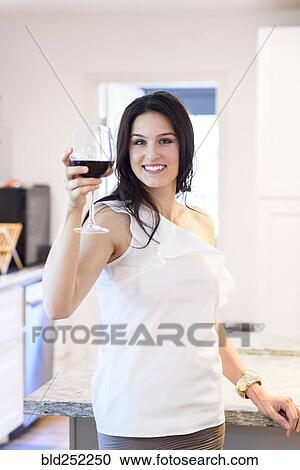 Stock Image - Smiling Caucasian woman toasting with red wine. Fotosearch