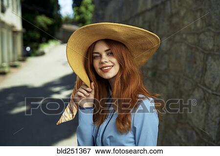 Stock Photo - Smiling Caucasian woman wearing hat near stone wall. Fotosearch