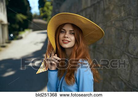 Stock Photo - Smiling Caucasian woman wearing hat near stone wall. Fotosearch