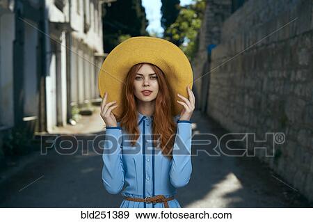 Stock Photo - Smiling Caucasian woman wearing hat near stone wall. Fotosearch