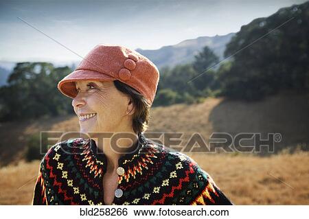 Stock Photograph - Smiling Caucasian woman wearing hat outdoors. Fotosearch
