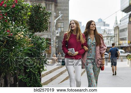 Smiling Caucasian women walking arm in arm in city View Large Photo Image Stock Photo - Smiling Caucasian women walking arm in arm in city. Fotosearch