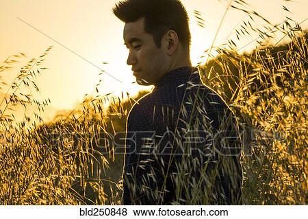 Stock Photo - Smiling Chinese man standing in field of wheat. Fotosearch