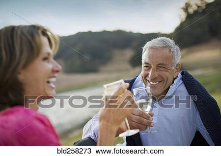 Stock Image - Smiling couple toasting with wine. Fotosearch
