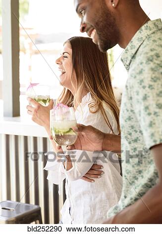 Smiling couple with cold drinks laughing outdoors View Large Photo Image Stock Image - Smiling couple with cold drinks laughing outdoors. Fotosearch