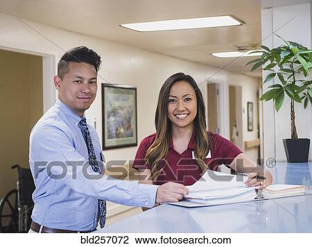 Stock Image - Smiling doctor and nurse in hospital. Fotosearch