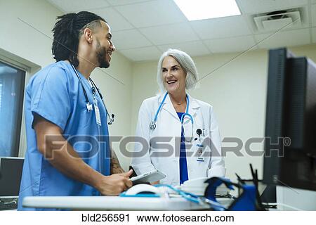 Stock Image - Smiling doctor and nurse talking. Fotosearch