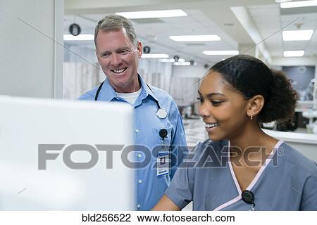 Stock Image - Smiling doctor and nurse using computer. Fotosearch
