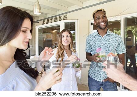 Smiling friends with cold drinks talking outdoors View Large Photo Image Stock Photograph - Smiling friends with cold drinks talking outdoors. Fotosearch