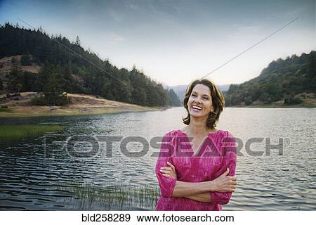 Smiling Hispanic man standing near lake View Large Photo Image Stock Photo - Smiling Hispanic man standing near lake. Fotosearch