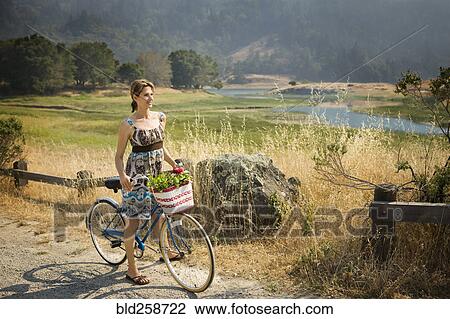 Smiling Hispanic woman standing with bicycle near river View Large Photo Image Stock Image - Smiling Hispanic woman standing with bicycle near river. Fotosearch