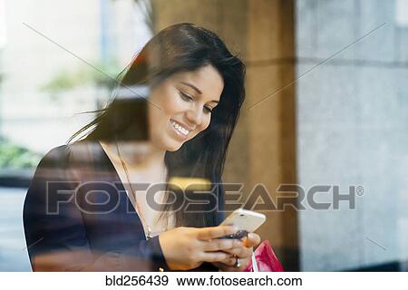 Smiling Hispanic woman texting on cell phone View Large Photo Image Stock Photo - Smiling Hispanic woman texting on cell phone. Fotosearch