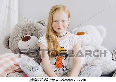 Stock Image - Smiling Middle Eastern girl sitting with large teddy bears. Fotosearch