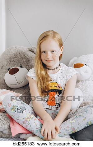 Stock Image - Smiling Middle Eastern girl sitting with large teddy bears. Fotosearch
