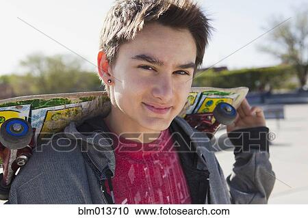 Smiling mixed race boy holding skateboard View Large Photo Image Stock Image - Smiling mixed race boy holding skateboard. Fotosearch