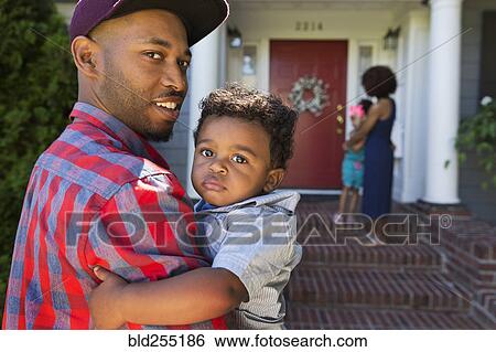 Stock Photograph - Smiling mixed race father carrying baby son. Fotosearch