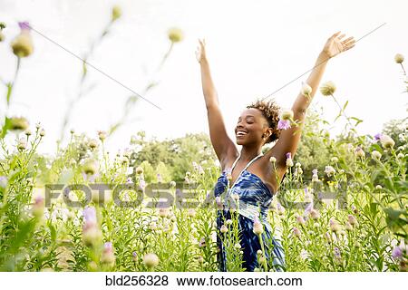 Stock Photo - Smiling mixed race woman celebrating in field of wildflowers. Fotosearch