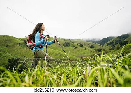Stock Photo - Smiling mixed race woman hiking with walking sticks. Fotosearch