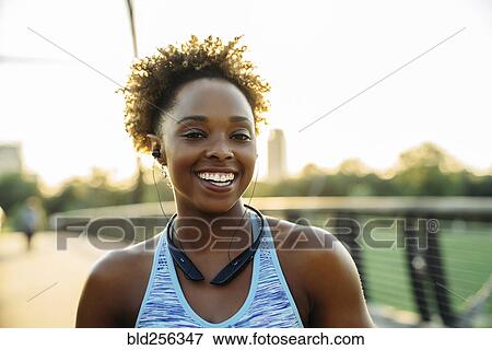 Smiling mixed race woman listening to earbuds on bridge View Large Photo Image Stock Photo - Smiling mixed race woman listening to earbuds on bridge. Fotosearch