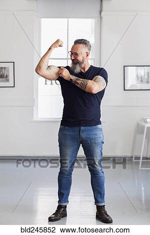 Smiling muscular Caucasian hipster man flexing biceps View Large Photo Image Stock Image - Smiling muscular Caucasian hipster man flexing biceps. Fotosearch