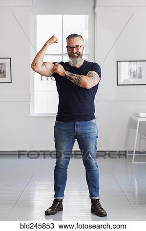 Smiling muscular Caucasian hipster man flexing biceps View Large Photo Image Stock Image - Smiling muscular Caucasian hipster man flexing biceps. Fotosearch