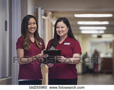 Stock Photography - Smiling nurses holding clipboard in hospital. Fotosearch