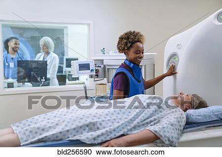 Stock Image - Smiling technician preparing scanner for patient. Fotosearch