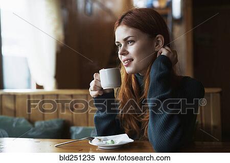 Stock Photography - Smiling woman drinking coffee in cafe. Fotosearch