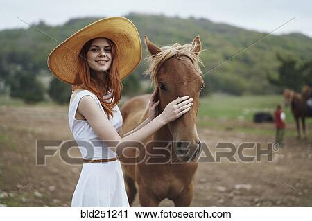 Stock Image - Smiling woman petting horse. Fotosearch
