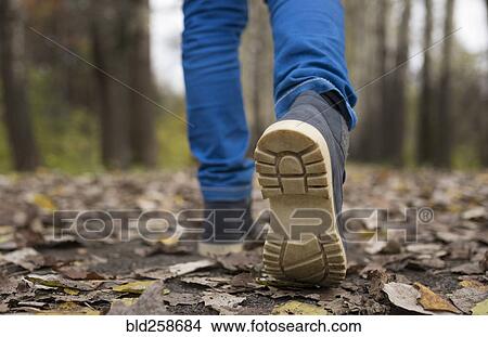 Picture - Sole of shoe of Caucasian boy walking on autumn leaves. Fotosearch