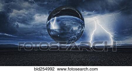 Stock Image - Sphere floating in remote landscape. Fotosearch