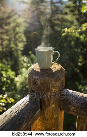Picture - Steaming coffee cup on wooden post. Fotosearch