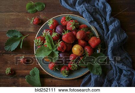 Stock Image - Strawberries and plums on plate. Fotosearch