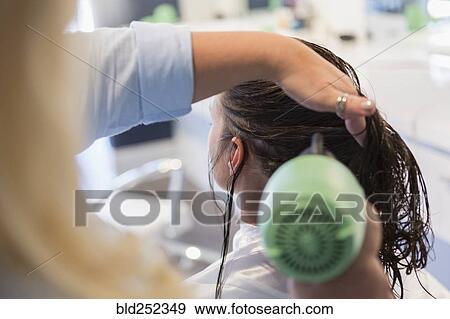 Stock Photo - Stylist drying hair of woman. Fotosearch