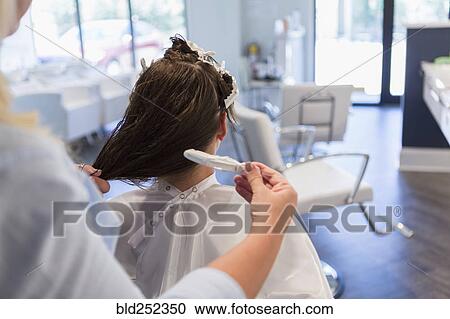 Stock Image - Stylist styling hair of woman. Fotosearch