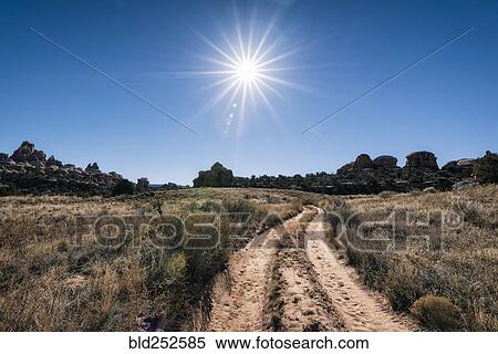 Stock Photography - "Sun in blue sky over desert path, Moab, Utah, United States". Fotosearch