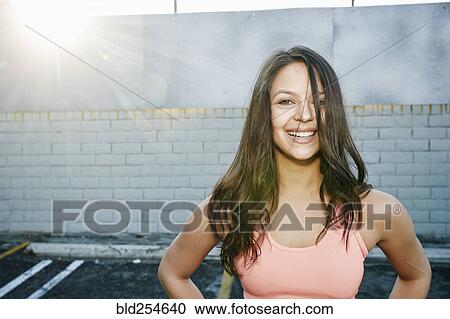 Stock Image - Sunbeams on smiling mixed race woman in parking lot. Fotosearch
