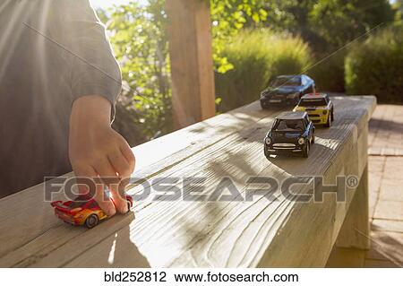 Stock Image - Sunshine on a Caucasian boy playing with toy cars. Fotosearch