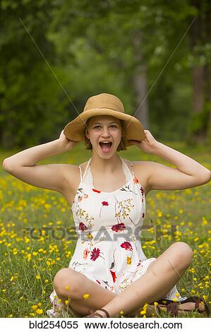 Stock Photography - Surprised Caucasian teenage girl sitting in field of flowers. Fotosearch