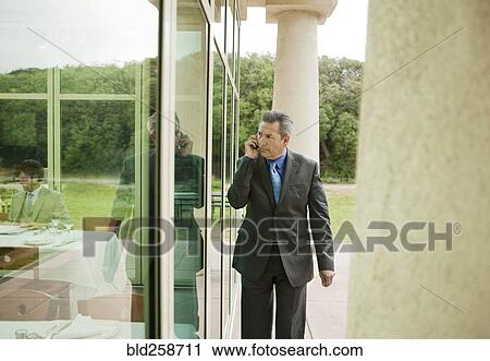 Suspecting Hispanic businessman talking on cell phone View Large Photo Image Stock Image - Suspecting Hispanic businessman talking on cell phone. Fotosearch