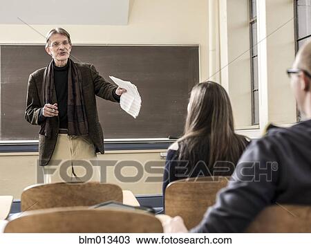 Stock Image - Teacher talking to students in classroom. Fotosearch