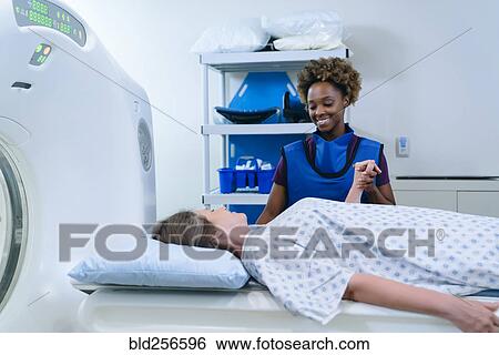 Stock Photograph - Technician holding hand of patient at scanner. Fotosearch