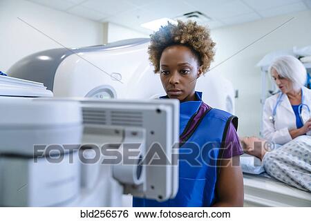 Stock Photograph - Technician preparing scanner for doctor comforting patient. Fotosearch