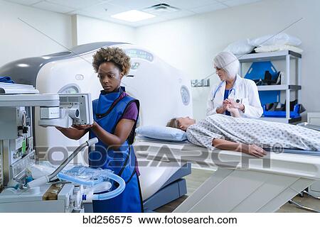 Stock Photography - Technician preparing scanner for doctor comforting patient. Fotosearch