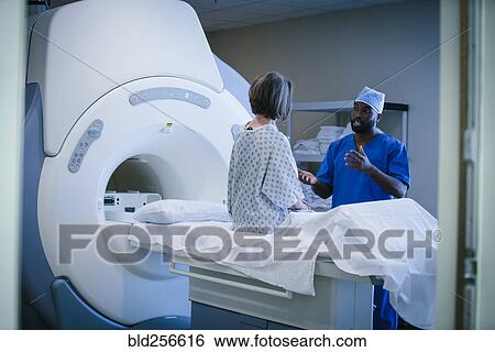 Stock Photograph - Technician talking to patient at scanner. Fotosearch